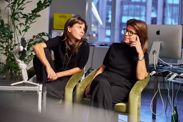 Zwei Frauen unterhalten sich in einem modernen Büro, eine am Telefon.