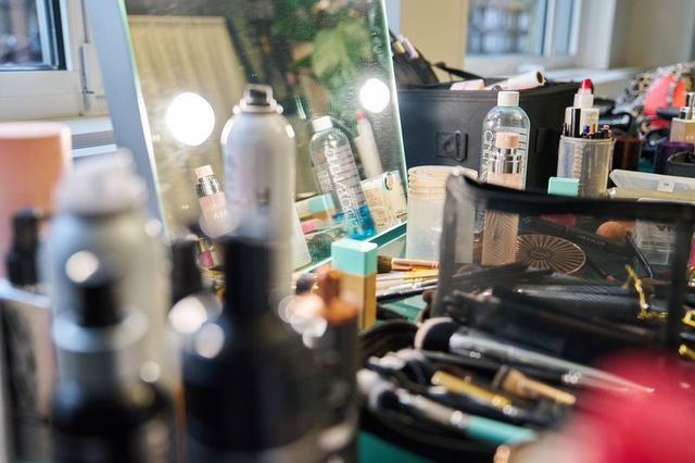 Beschreibender Alt-Text: „Unordentlicher Friseur-Arbeitsplatz mit Werkzeugen, Sprays und Kosmetik.“